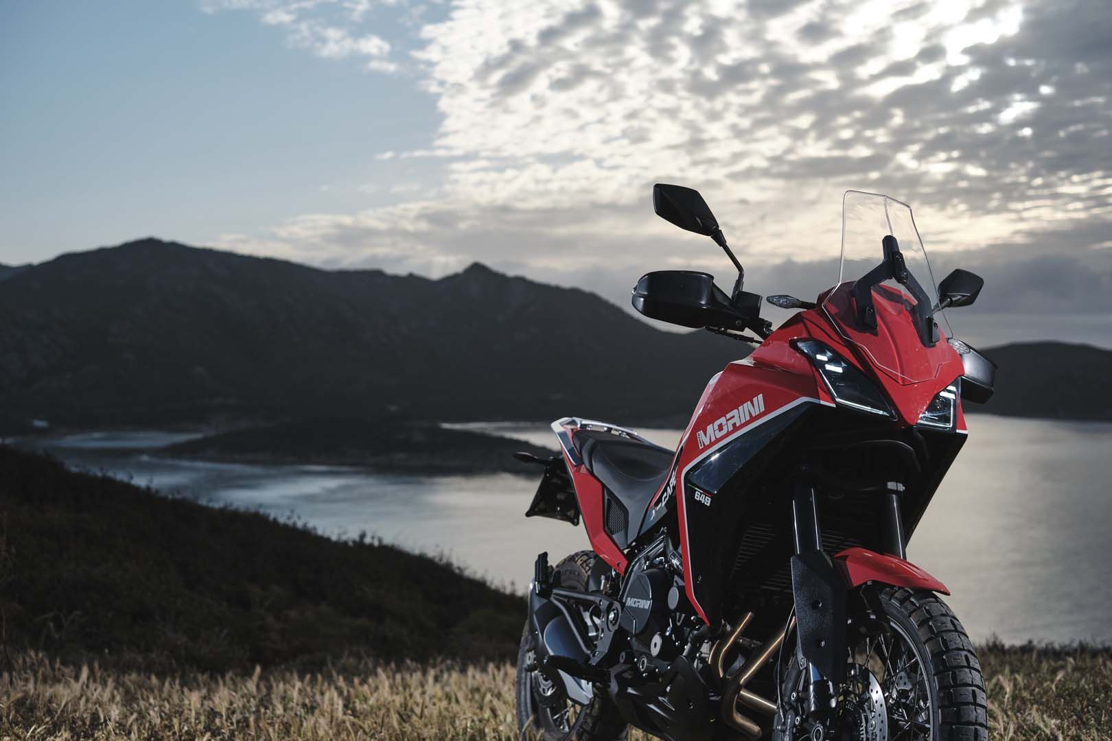 全新Moto Morini X-Cape冒险摩托车在崎岖地形上的视图，具有华丽的热带景色。