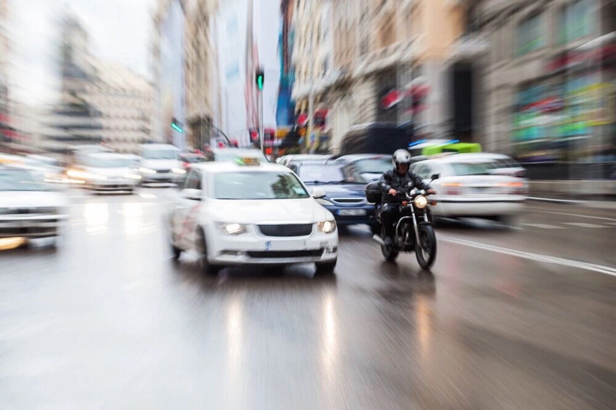 一辆汽车和一个骑摩托车的人在雨天的街道上。图片由卡夫公司提供