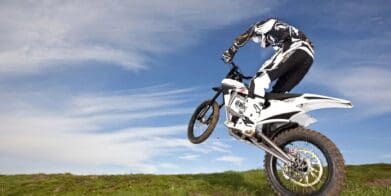 零摩托车和骑手跳跃一座小山。媒体来自沥青和橡胶。