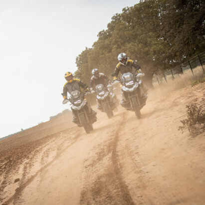 正面形象的三个骑手在宝马摩托车骑在一条土路上。