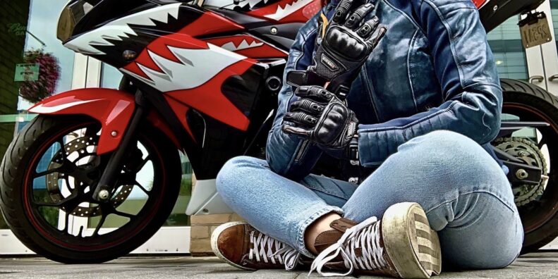 作者盘腿坐在前面的摩托车穿着赛车美国女性的维修站手套