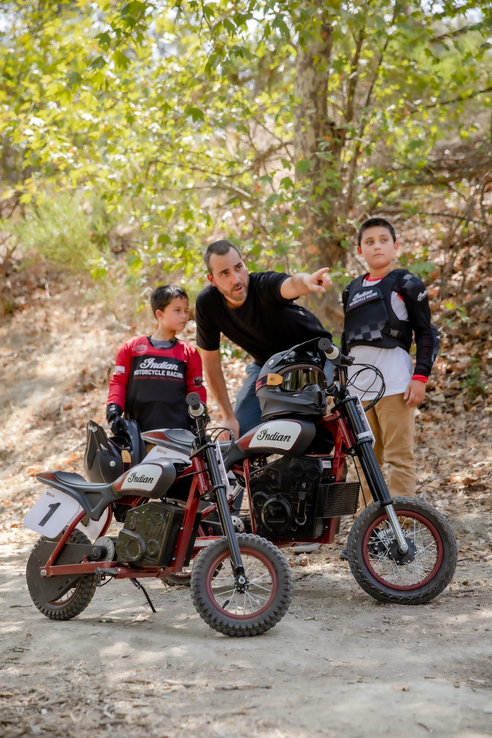 一个成熟的骑手和两个年轻的骑手正在试用来自印度摩托车公司的新sFTR迷你摩托车——一种小型骑行社区可用的电动青年自行车