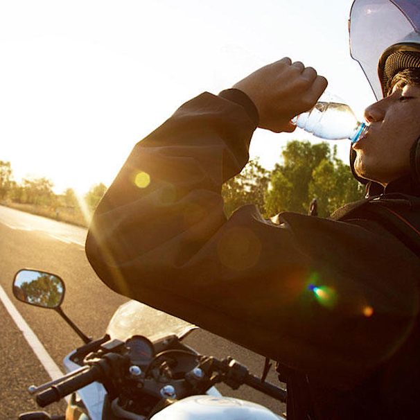 女性摩托车骑手饮用水上休息。照片由Orangeville BMW经销店。
